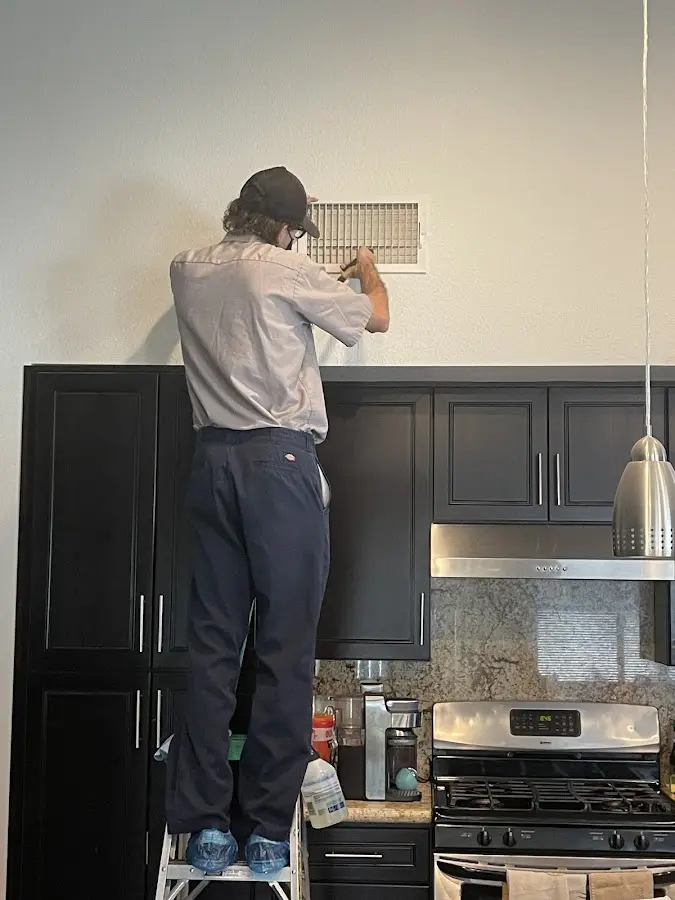 Technician inspecting an air vent during HVAC service in Helena-West Helena